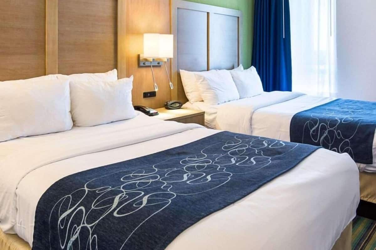 Een hotelkamer met twee bedden, een nachtkastje, een lamp en uitzicht.