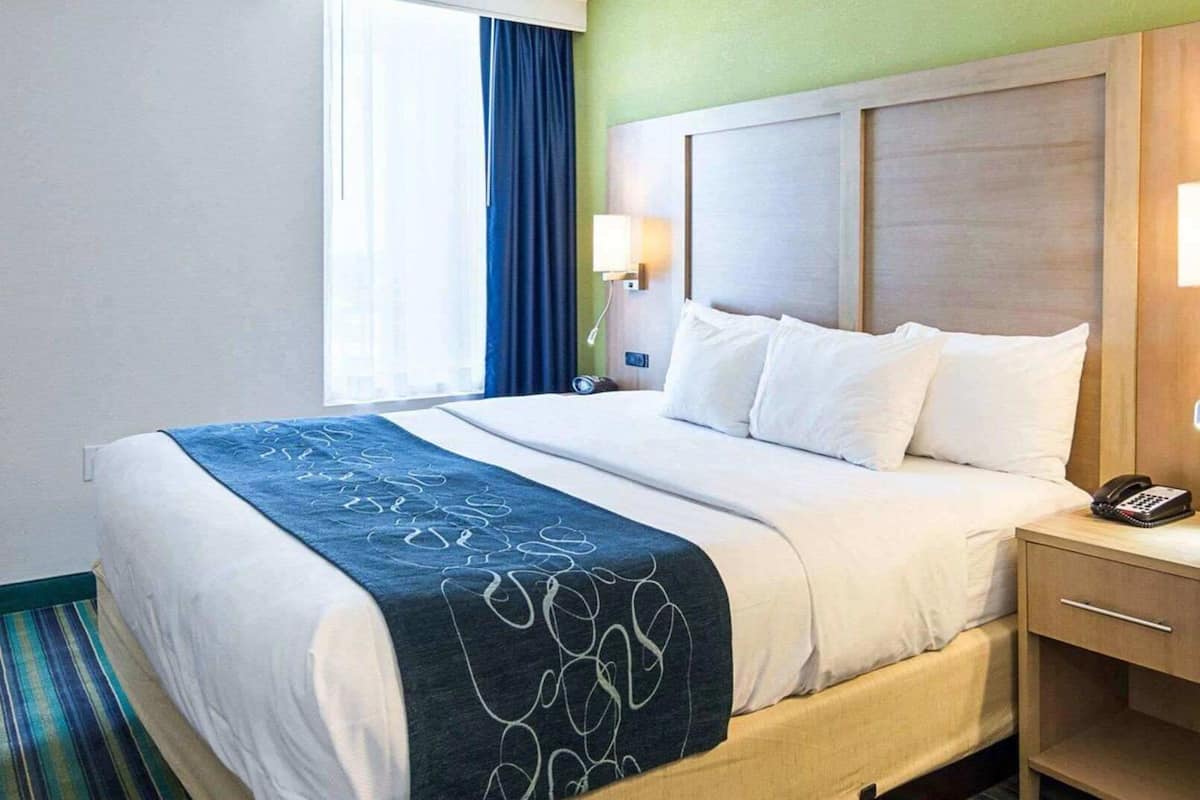 Een hotelkamer met een bed, nachtkastje, lamp en telefoon.