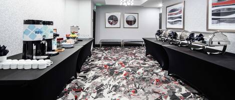 A conference room with a patterned carpet, a buffet setup, and framed artwork on the walls.