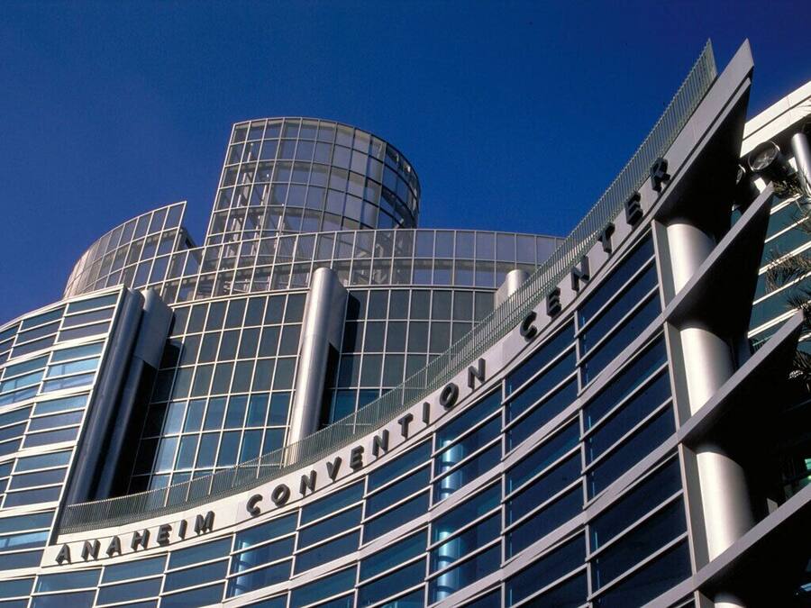 El exterior del Centro de Convenciones de Anaheim, con fachada de vidrio moderna y una estructura cilíndrica destacada.