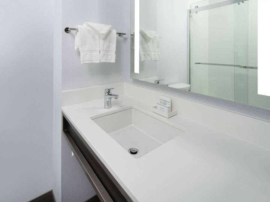 A modern bathroom with a white sink, a mirror, and two towels hanging on a towel rack.