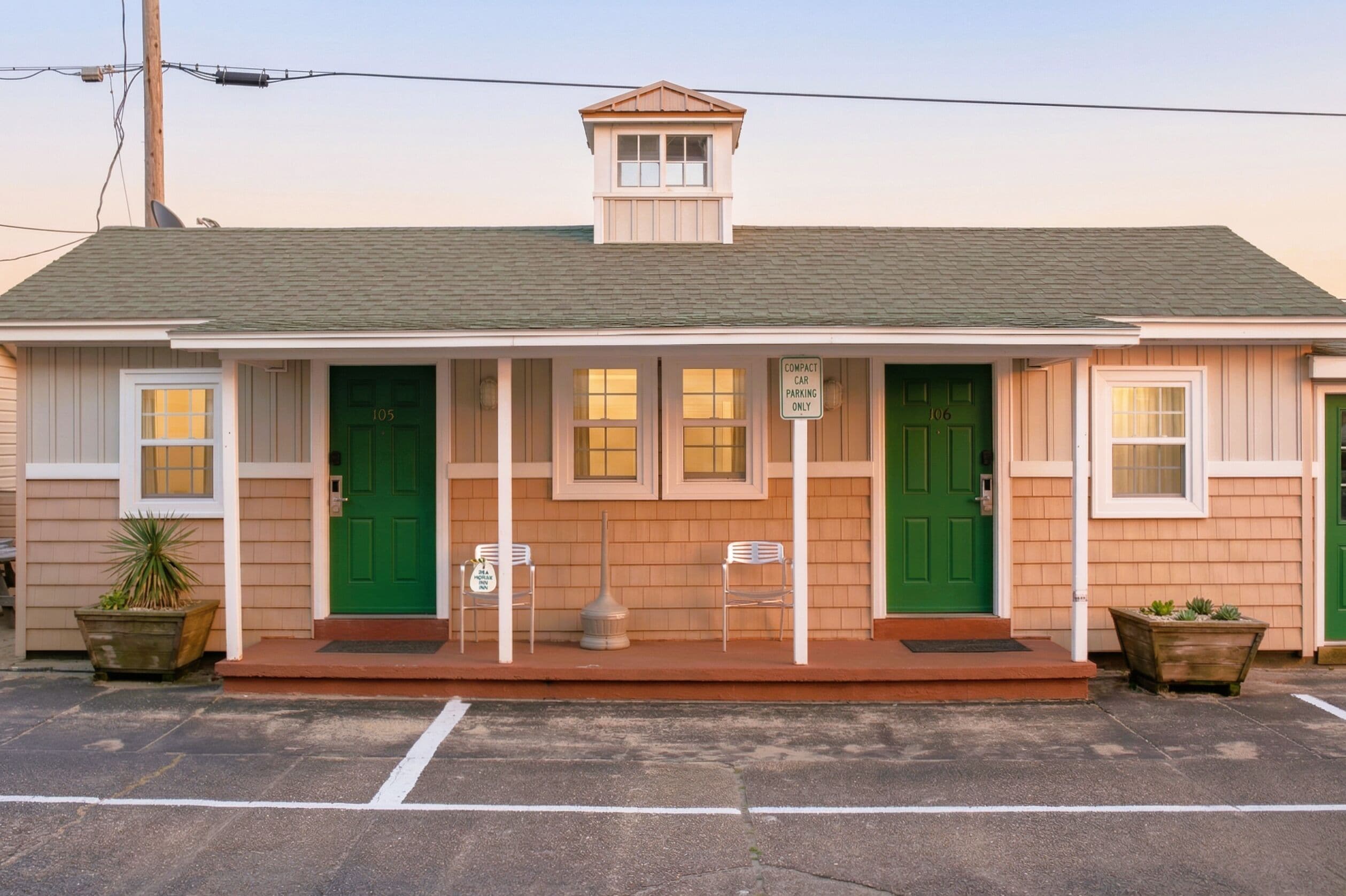 A small building with two green doors, numbered 105 and 106, and a sign indicating compact car parking.