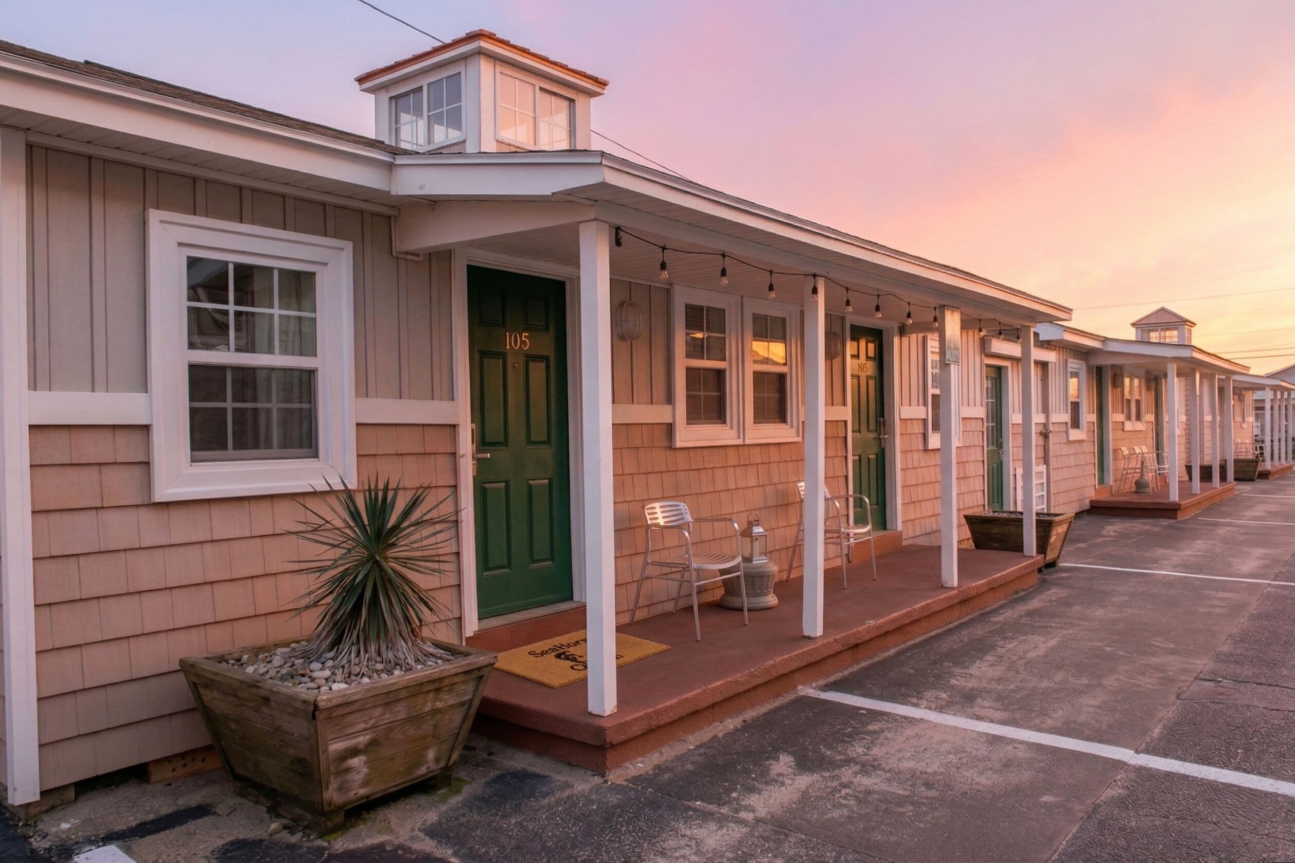A row of single-story buildings with a porch, a green door, and a mailbox.
