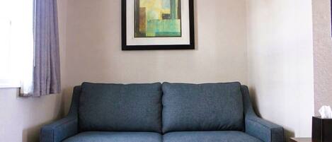 A grey sofa with a framed abstract painting above it.