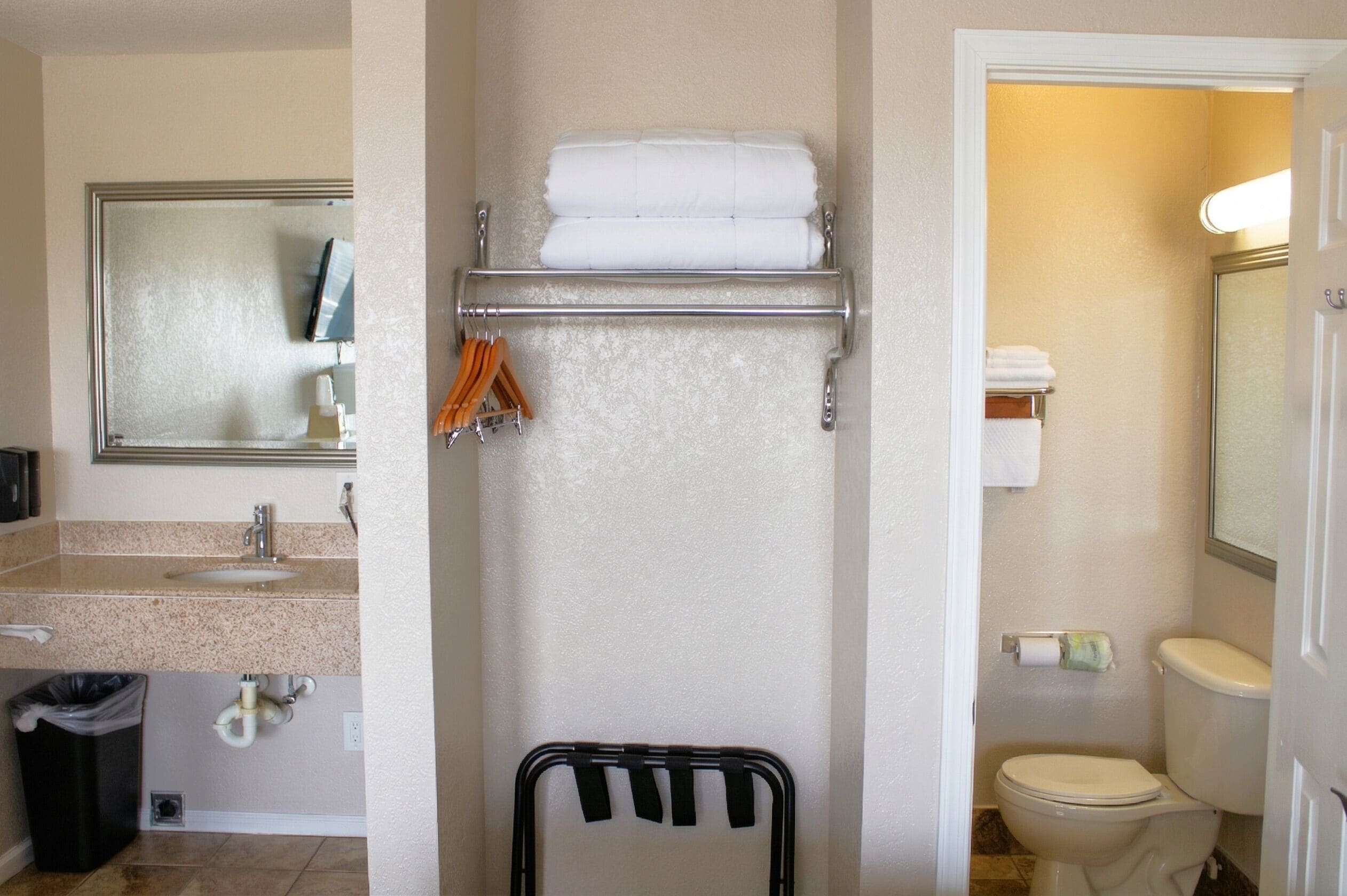 Un baño con lavamanos, espejo, toallero y retrete.