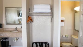 Un baño con lavamanos, espejo, toallero y retrete.