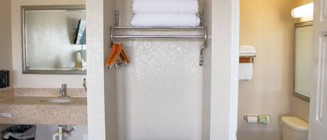 Un baño con lavamanos, espejo, toallero y retrete.