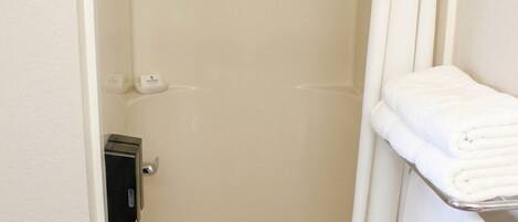 A walk-in shower with a glass door, a hand dryer, and a towel rack with folded towels.