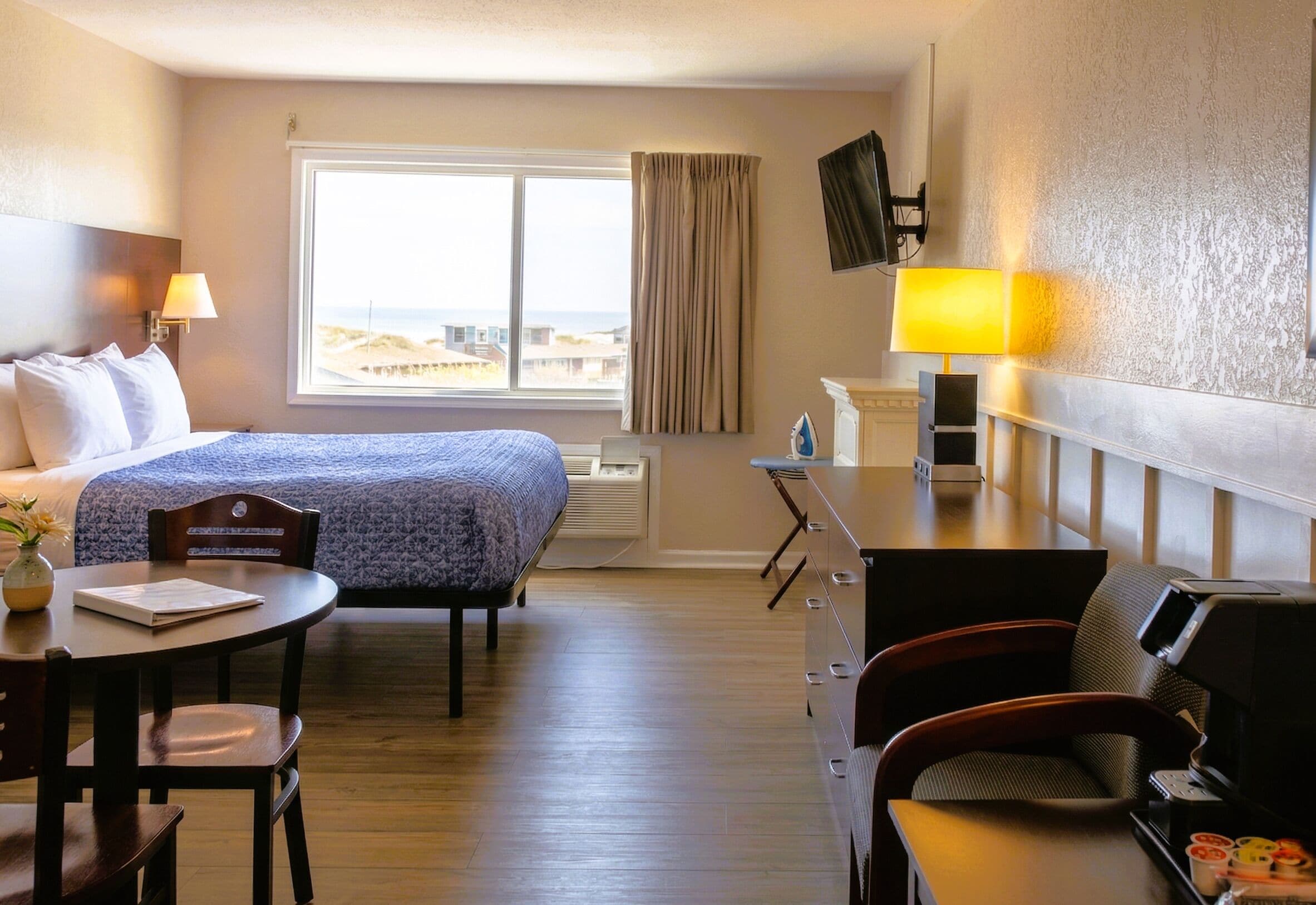 Una habitación de hotel con cama, escritorio, silla y televisor.