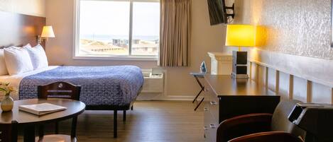 Una habitación de hotel con cama, escritorio, silla y televisor.