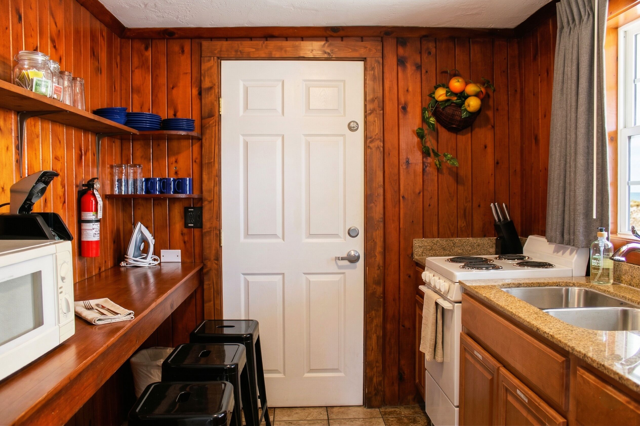 A kitchen with wooden walls, a white door, and a sink.