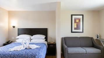 A hotel room with a bed, a nightstand, a sofa, and a framed picture on the wall.