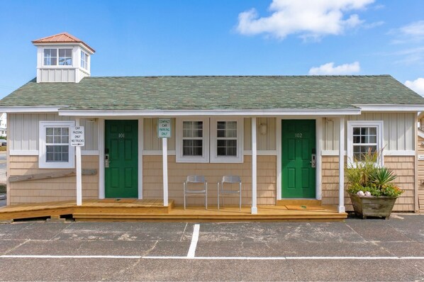 A small building with two green doors, numbered 101 and 102, and a sign indicating compact car parking only.