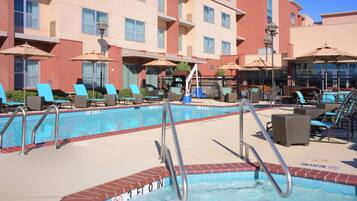 Een buitenzwembad, ligstoelen bij het zwembad