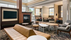 Un hall d’hôtel spacieux, doté d’une cheminée, de sièges confortables et d’un téléviseur à écran plat.