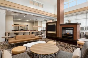 A spacious lobby with a fireplace, seating area, and a dining setup.