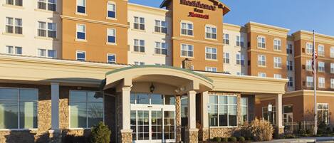 A multi-story hotel with a beige and brown facade, a prominent entrance with a glass door, and a sign indicating it is a Marriott hotel.