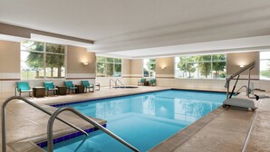 Une piscine dotée d’une terrasse carrelée, de chaises longues et d’un intérieur baigné de lumière.