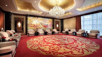 Habitación de hotel con una alfombra redonda grande, un candelabro y un cuadro floral de gran tamaño en la pared.