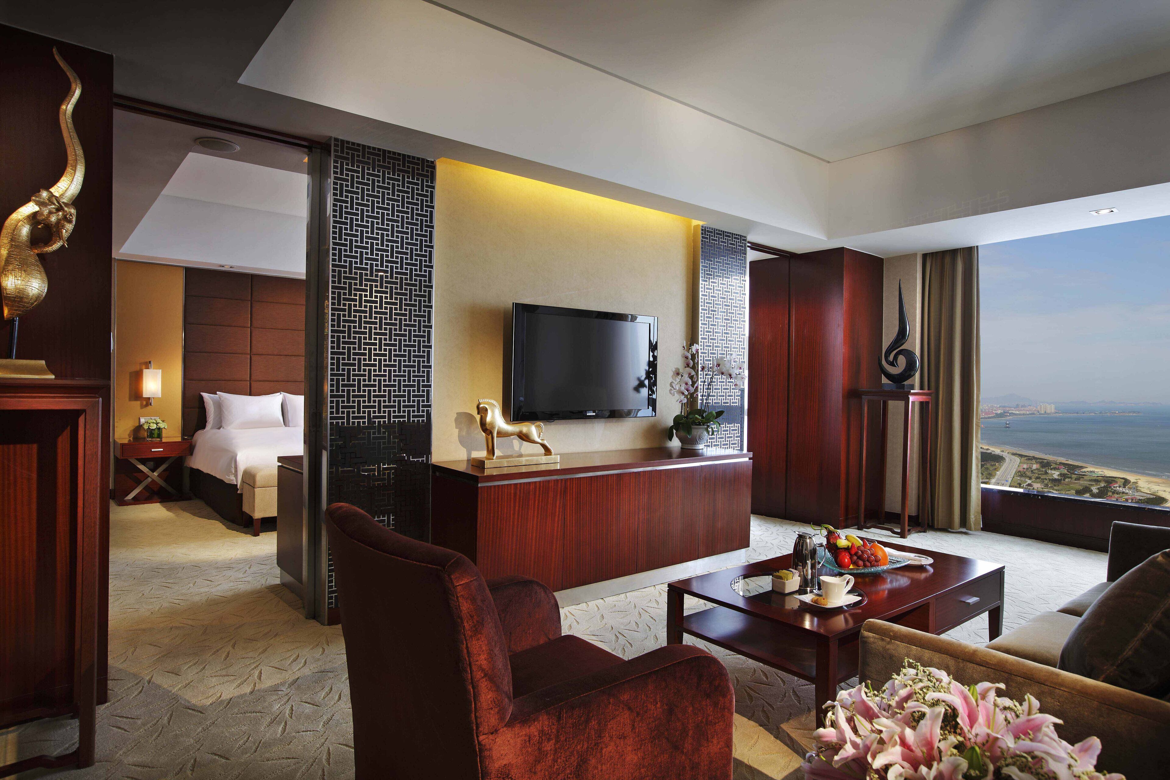 Hotelkamer met een bed, een bureau met een flatscreen televisie, een zithoek met een salontafel en uitzicht op de oceaan.