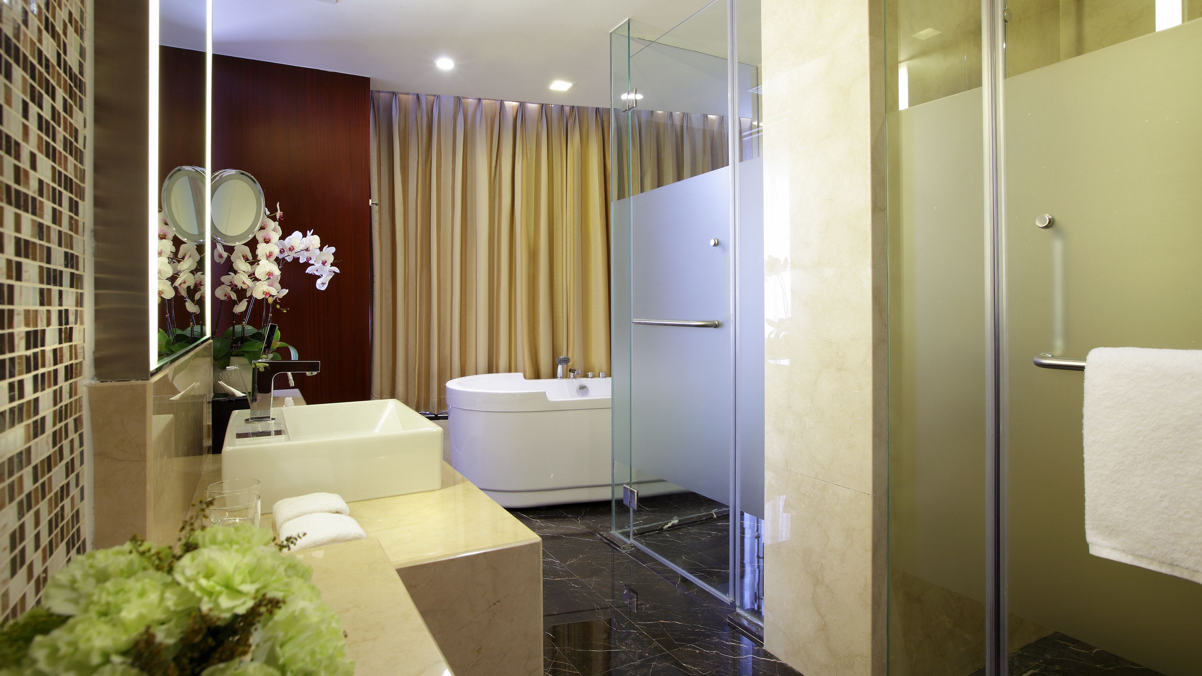 A modern bathroom with a bathtub, a glass-enclosed shower, and a vanity with a mirror.