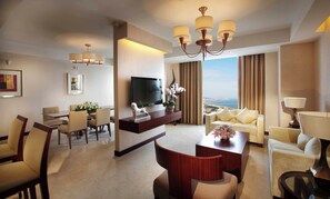 A hotel room with a TV, seating area, dining table, and a view of the sea. - Crowne Plaza Yantai Seaview by IHG (Yantai)