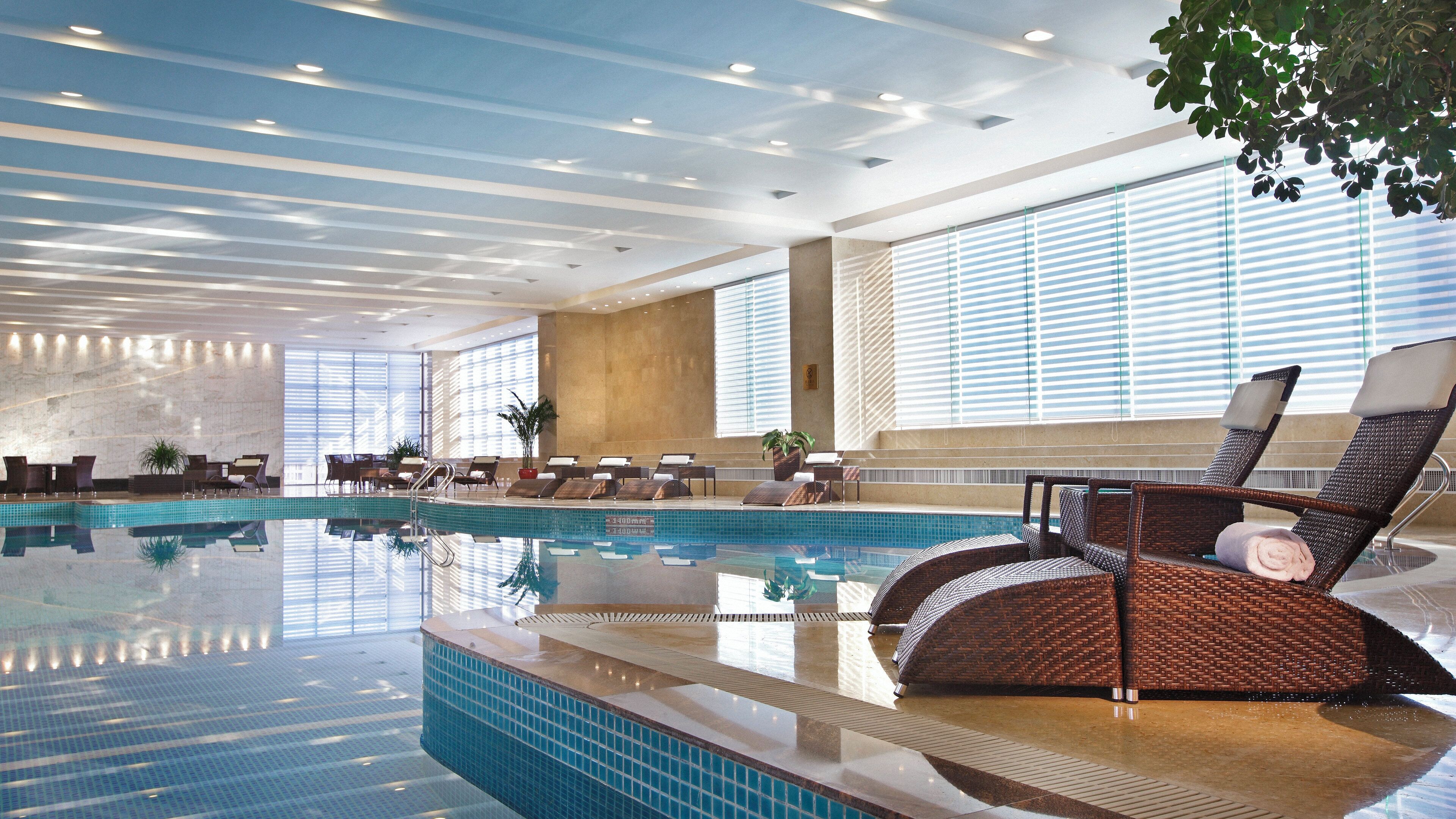 An indoor swimming pool with lounge chairs and a sunbed.