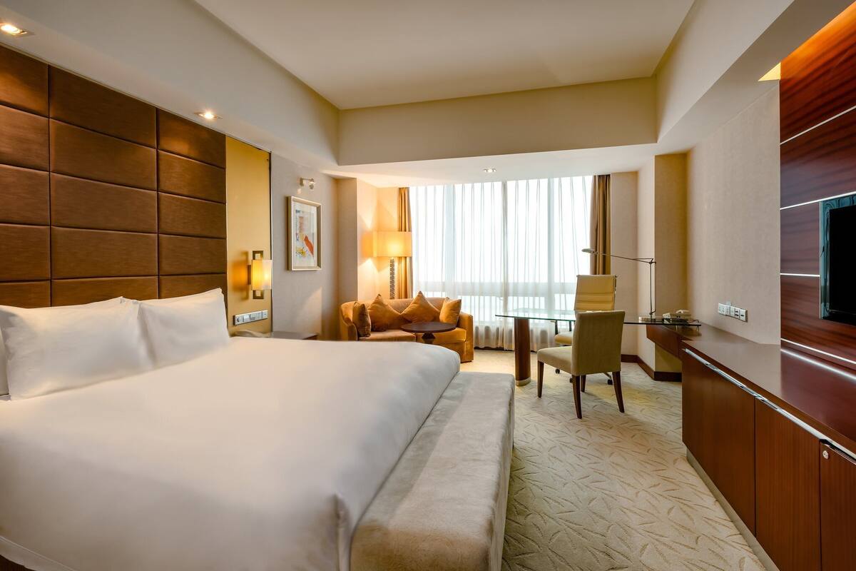 A hotel room with a large bed, a desk, a chair, and a TV.