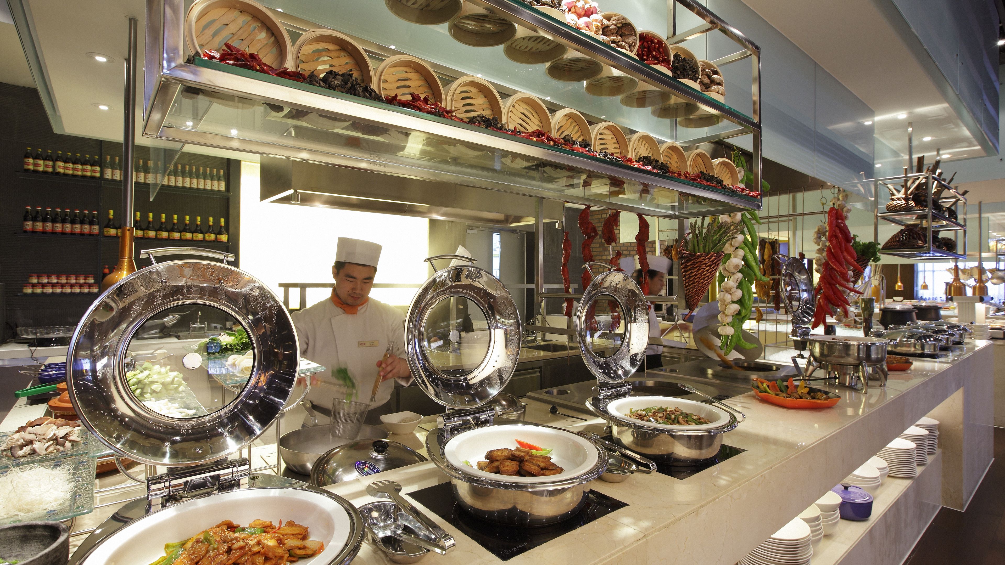 A buffet setup with various food items and a chef preparing food.
