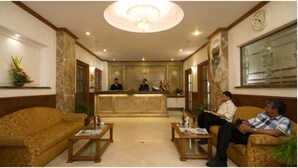 Um saguão de hotel com uma mesa de recepção, dois sofás e um candelabro.