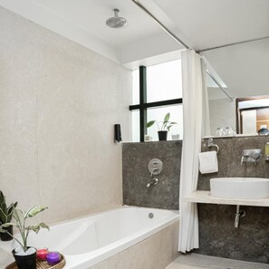 A modern bathroom with a bathtub, a sink, and a shower area. - Monarch Luxur (Bengaluru)