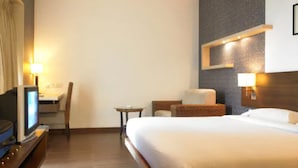 A hotel room with a large bed, a desk with a chair, a TV, and two wall-mounted lamps. - Hotel Satkar Residency (Thane)