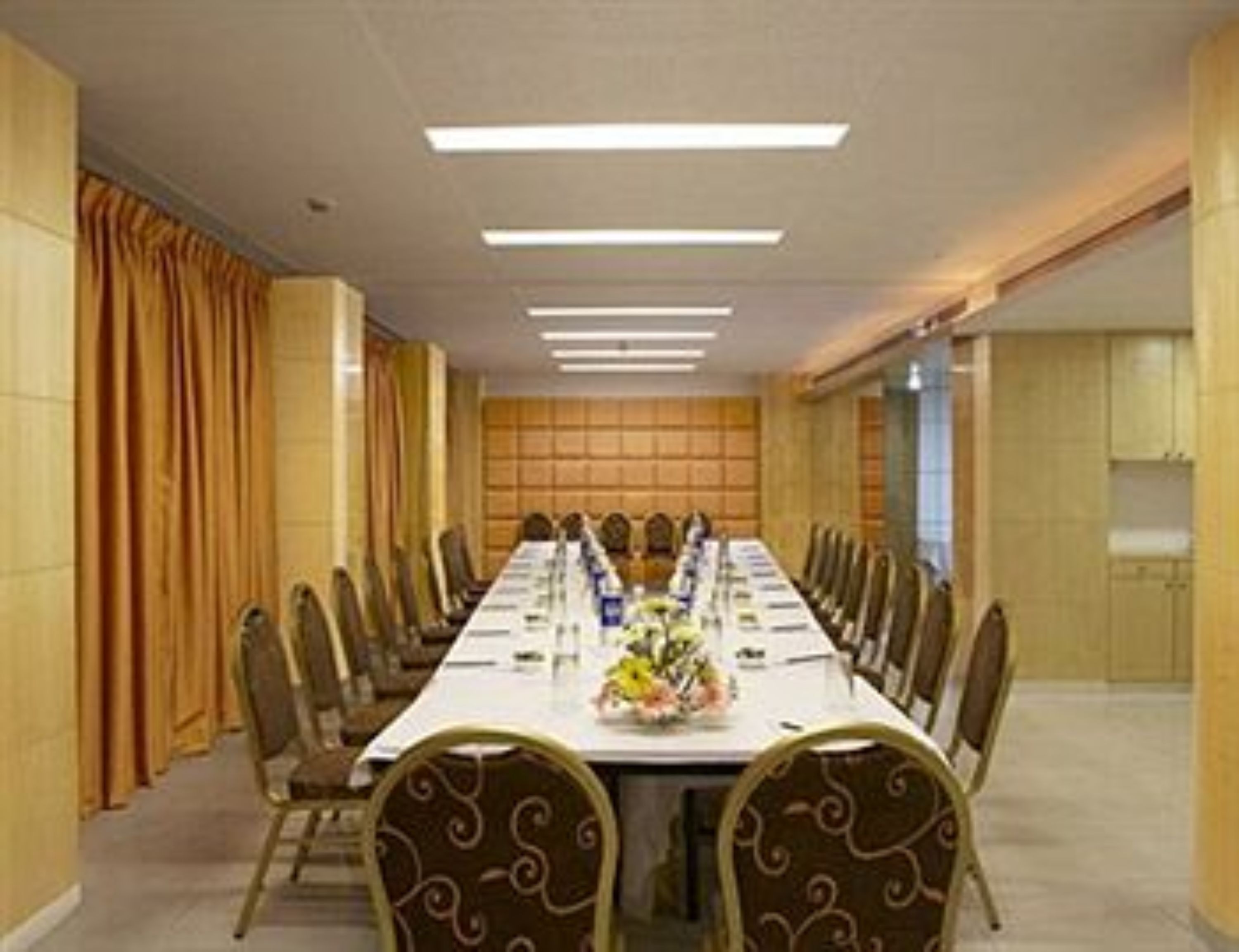 A conference room with a long table, chairs, and a floral centerpiece.