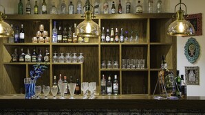 A bar area with shelves of liquor bottles and glasses, a decorative vase, and hanging light fixtures. - Hotel Park Residency (New Delhi)
