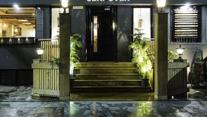 The entrance to The Clay Oven with steps leading up to the door, potted plants on either side, and a sign above the door. - Hotel Park Residency (New Delhi)