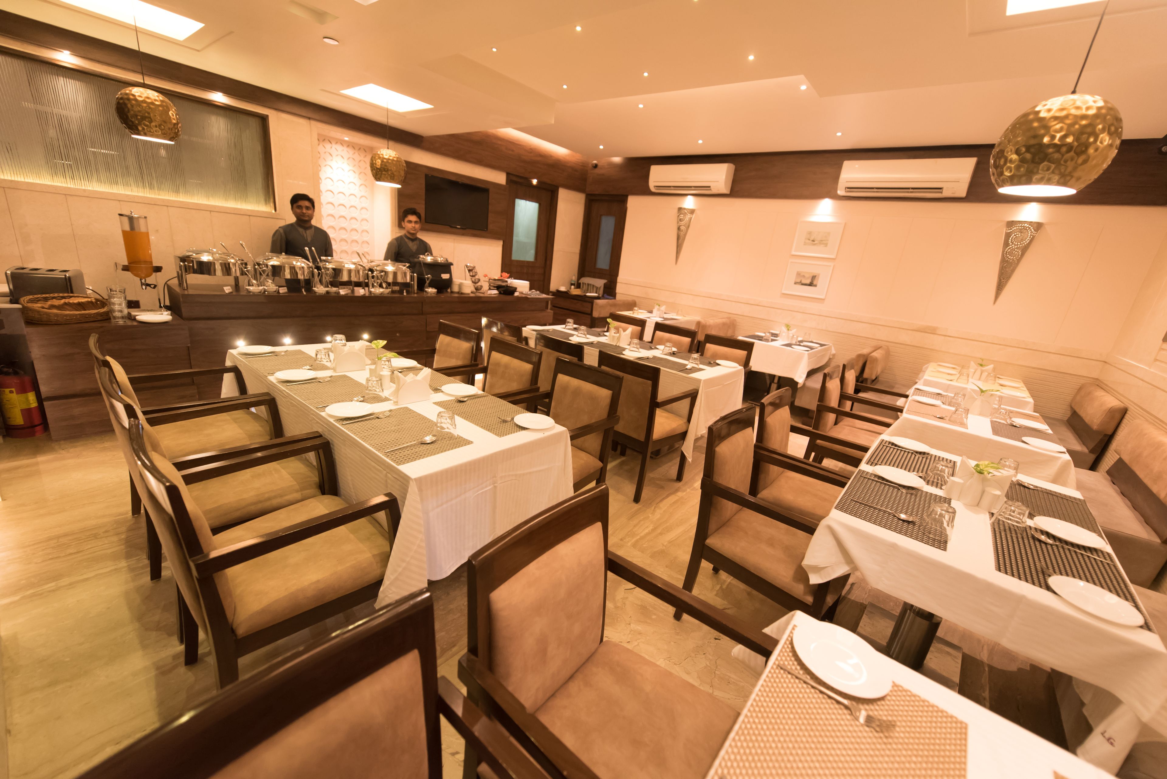 A restaurant with multiple tables set for dining, a bar area, and a counter with staff.