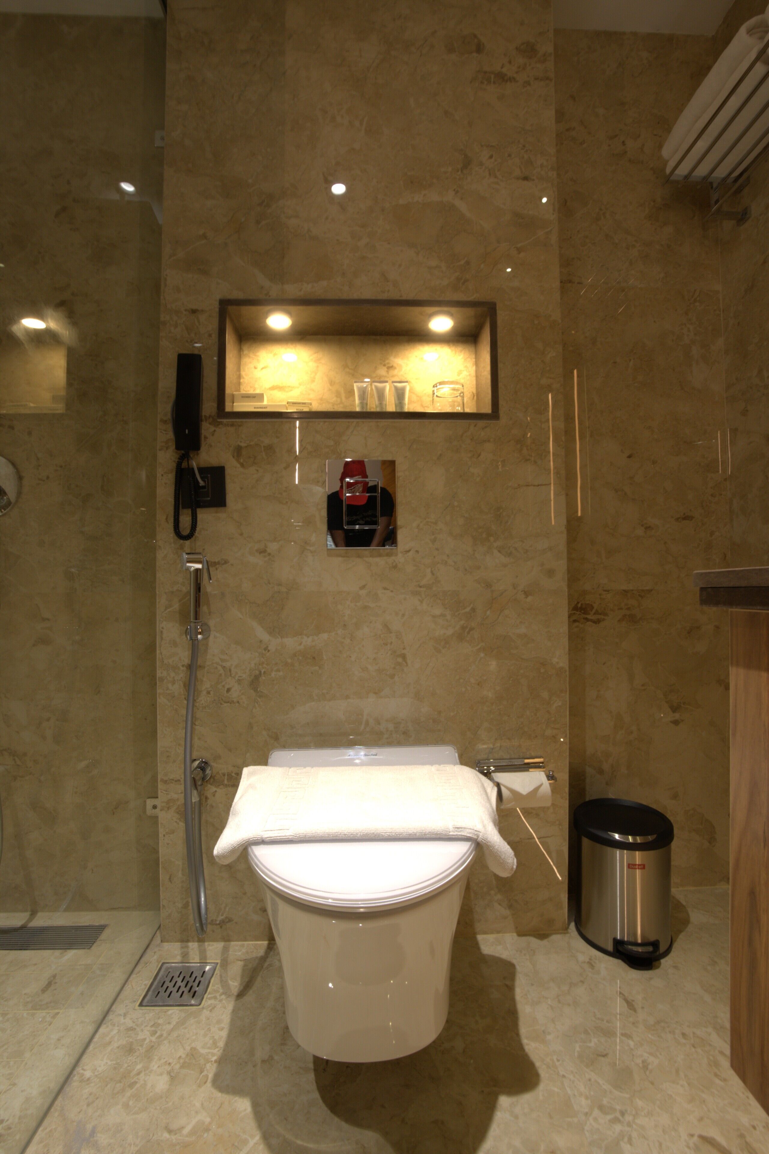 A modern bathroom with a toilet, a shower, a sink, and a trash can.