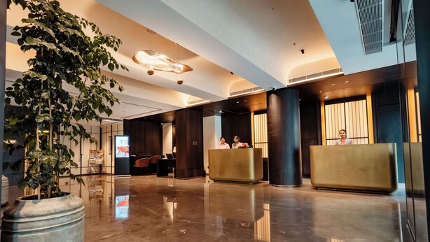 A modern lobby with a reception desk, seating area, and a large potted plant. - Travancore Court (Kanayannur)