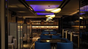 A modern bar area with blue seating, a bar counter, and a television screen. - Travancore Court (Kanayannur)