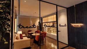 A modern cafe interior with a glass partition, comfortable seating, and a decorative sign. - Travancore Court (Kanayannur)