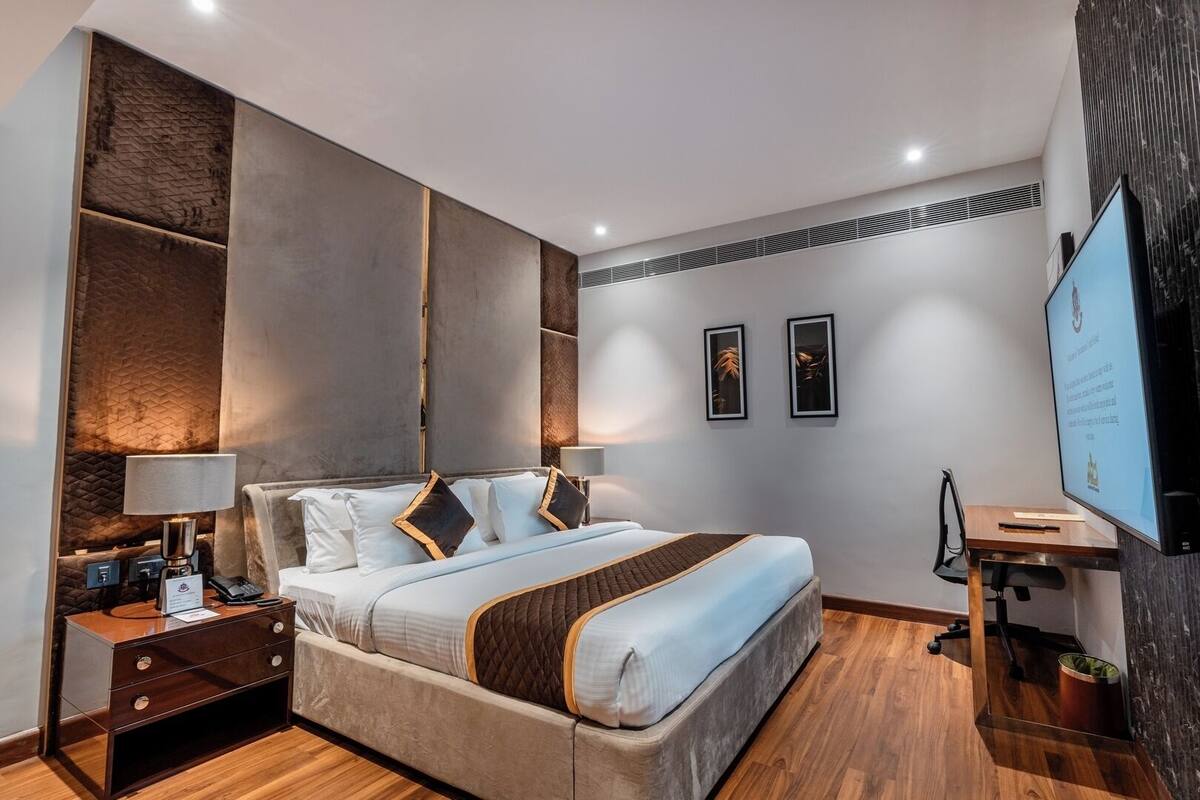 A modern hotel room with a large bed, bedside tables, a desk, and a television.