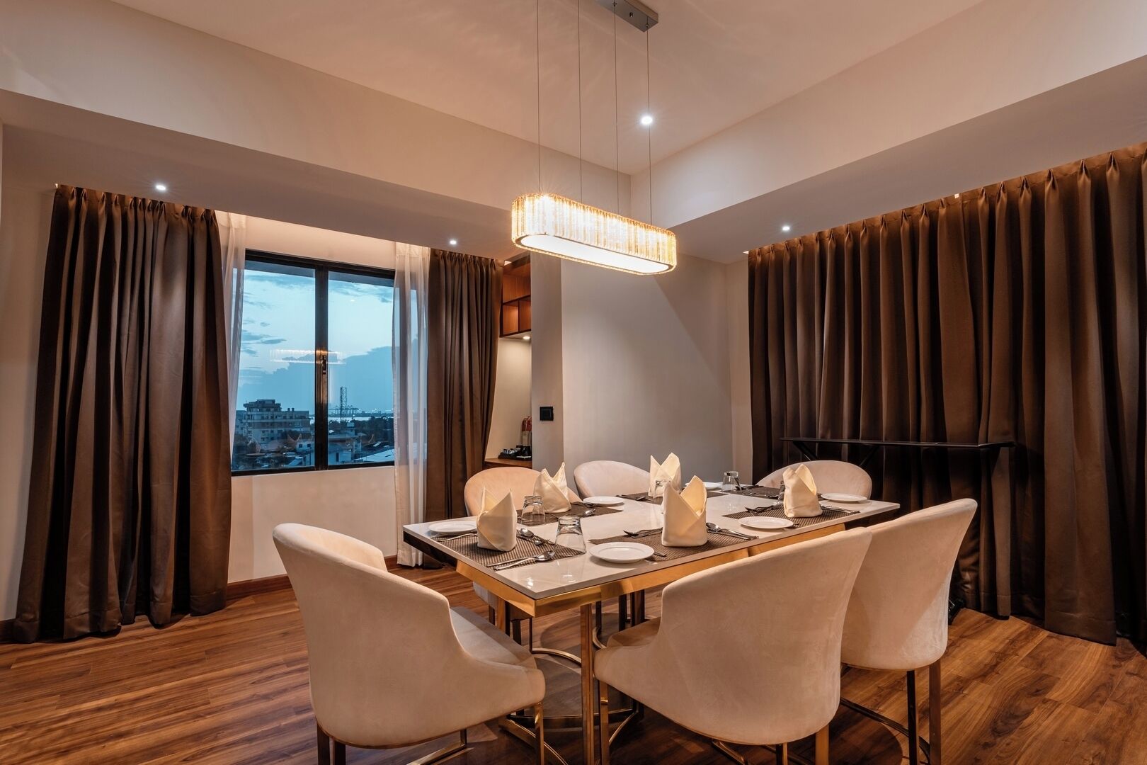A dining room with a table set for four, large windows, and curtains.