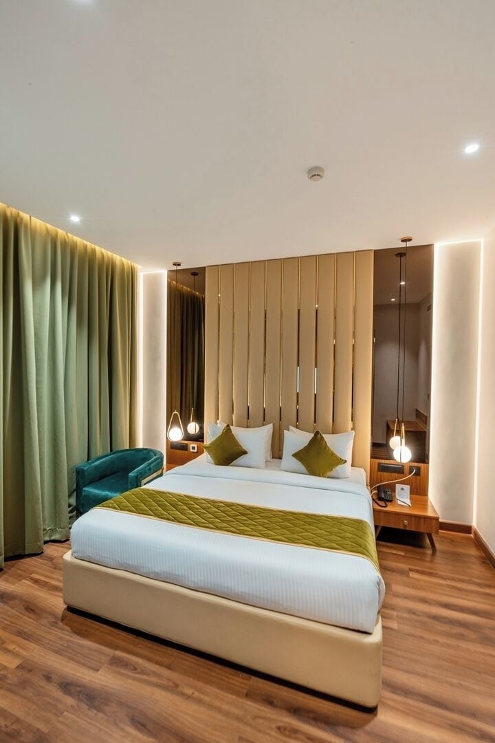 Una habitación de hotel moderna con una cama grande, una mesita de noche, una silla y una cortina.