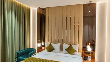 Una habitación de hotel moderna con una cama grande, una mesita de noche, una silla y una cortina.