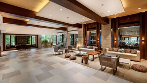 A spacious lobby with a checkered floor, a sofa set, and a dining area with a stone wall and large windows. - The Resort Mumbai (Mumbai)