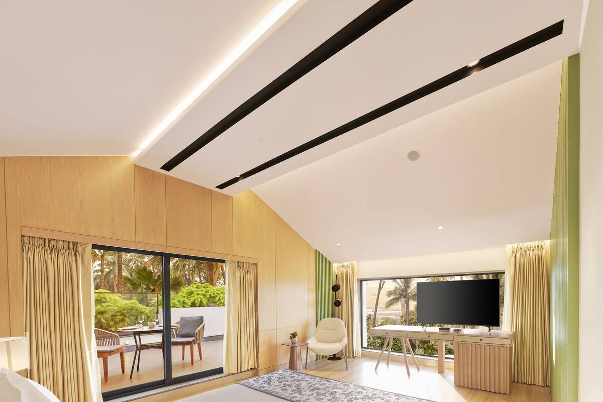 A modern bedroom with a large bed, a TV, and a balcony with outdoor seating.