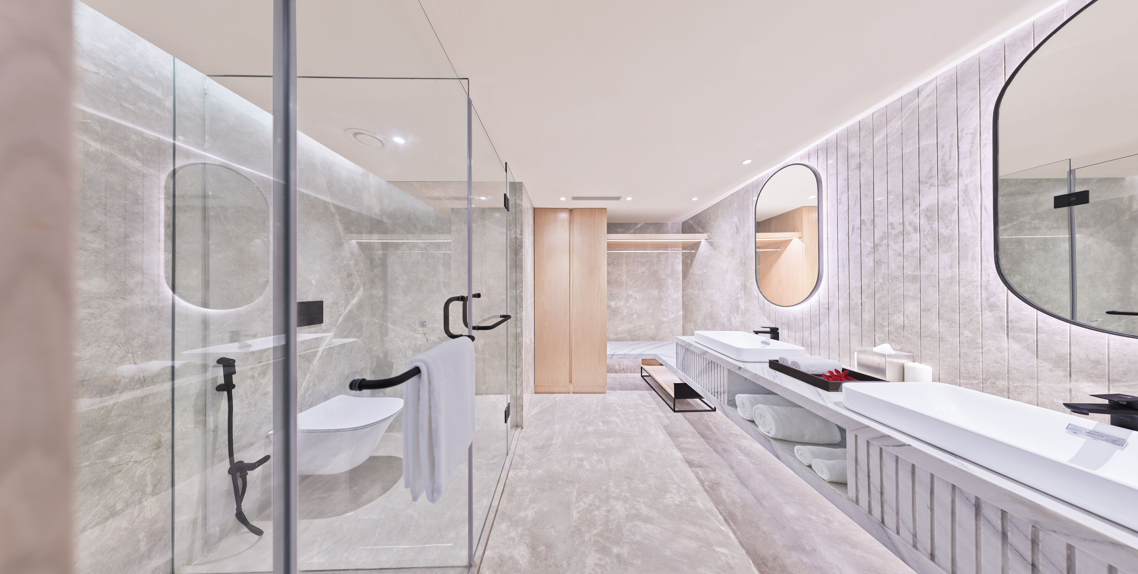 Un bany modern amb una cabina de dutxa de vidre, un mirall gran i un moble de bany amb un lavabo i barra de tovalloles.