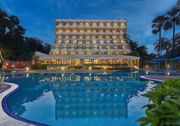 Un hotel de varios pisos con una piscina delantera.