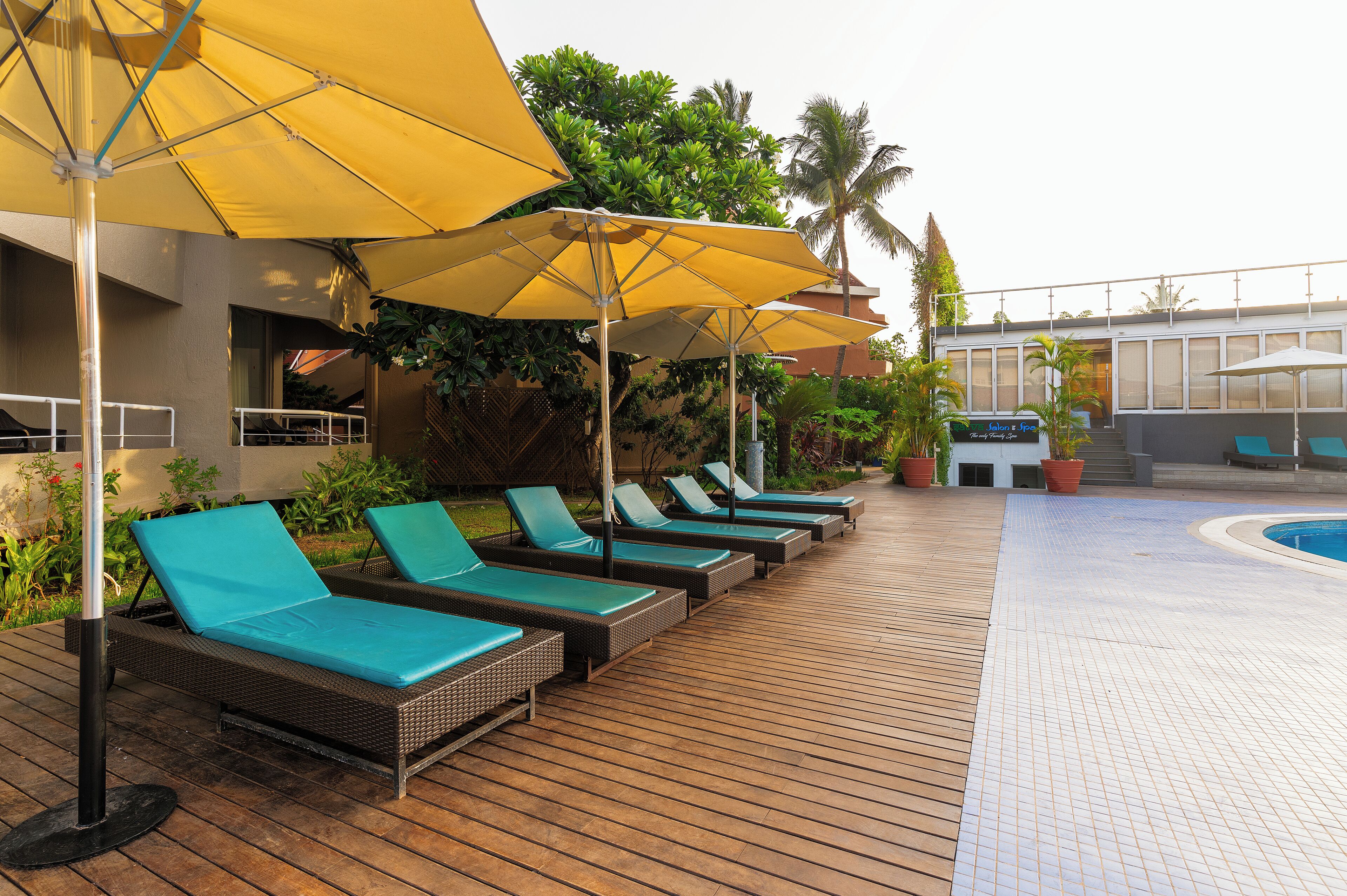 A poolside area with lounge chairs and yellow umbrellas.