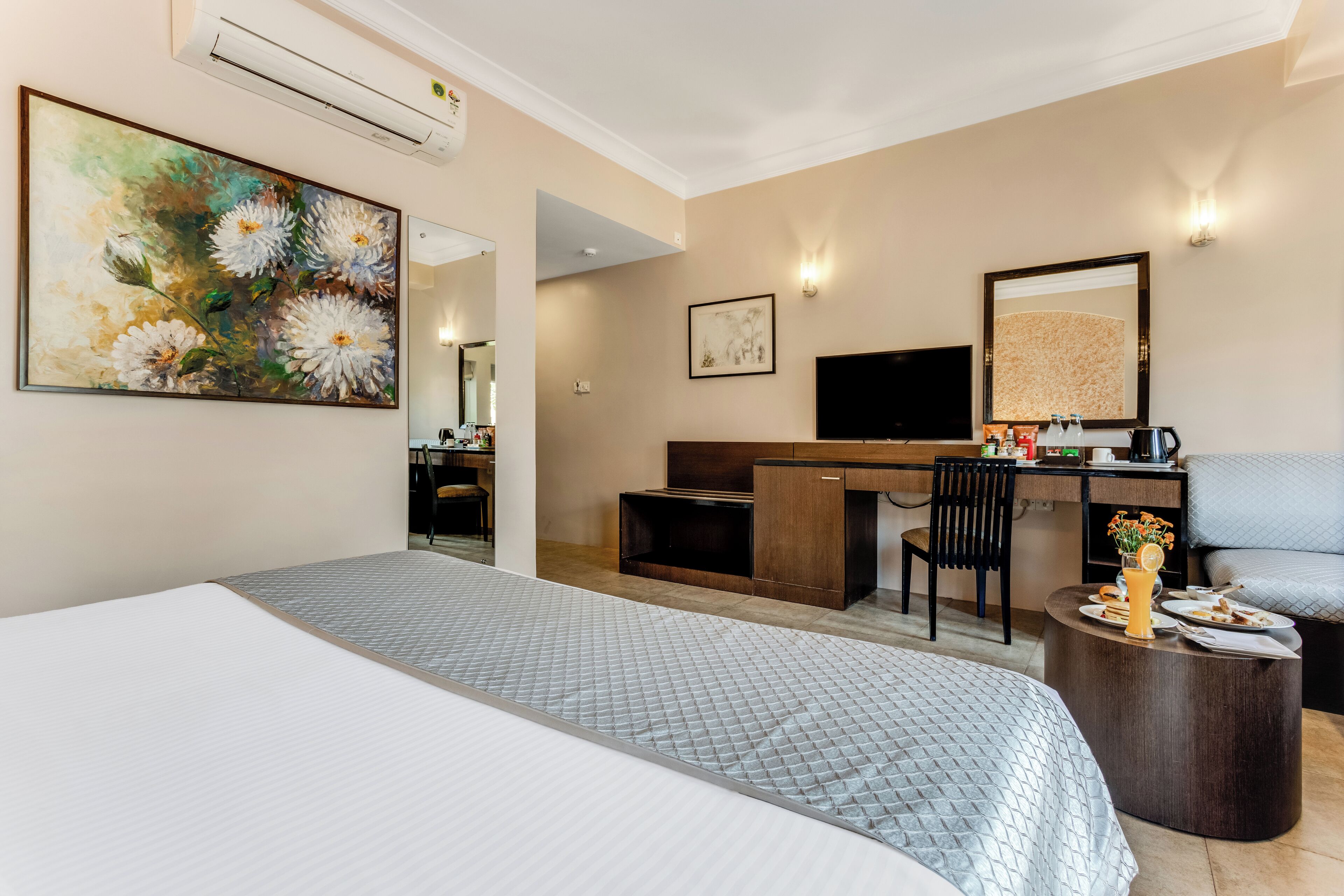 Una habitación de hotel con cama, escritorio, silla, televisión y una mesita de centro.